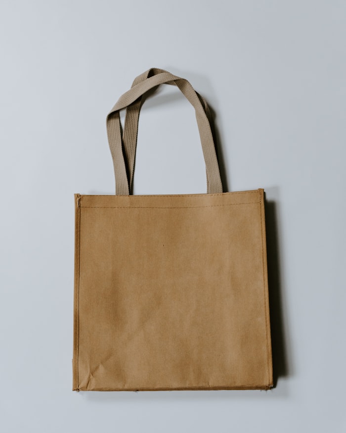 Tote bag and packaging on a plain surface, used as an application reference.